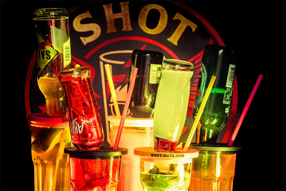 Fünf Shot-Mate-Drinks mit verschiedenen Flaschen und farbigen Booze Dock Aufsätzen vor großem Logo im Hintergrund.