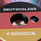Shot-Mate Fan Dock Deutschland in den Farben Schwarz, Rot und Gold. Der Getränkehalter bietet eine Öffnung für Flaschen sowie eine separate Halterung für Strohhalme und sorgt für Ordnung bei Getränken auf Fußballpartys und Public Viewings.