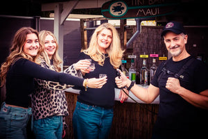 Mehrere Personen stoßen auf einer Party an, während ein Shot-Mate Getränkerucksack mit Trinkschlauch für das Ausschenken von Getränken genutzt wird. Ideal für Veranstaltungen, Festivals und Events.
