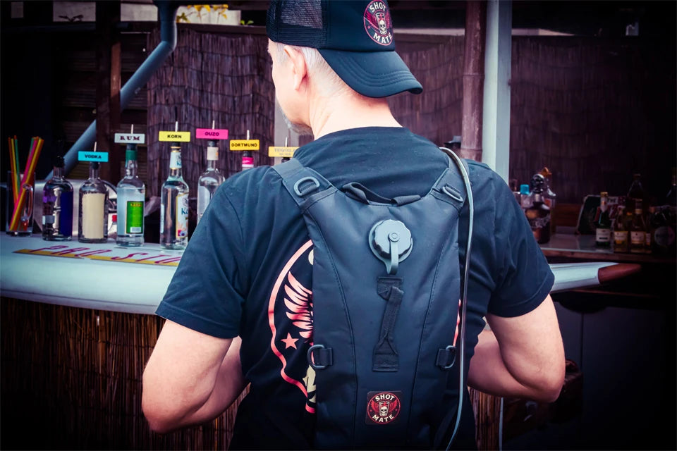 Person trägt einen Shot-Mate Getränkerucksack mit Trinkschlauch vor einer Bar. Der mobile Trinkrucksack eignet sich für Festivals, Partys, Veranstaltungen und Events.
